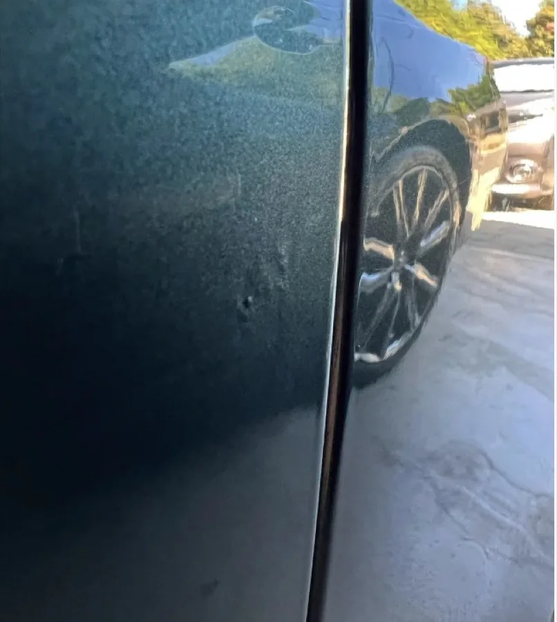 The botched door panel shared in the r/PaintlessDentRepair thread, with a visible lift mark and ripple near the edge