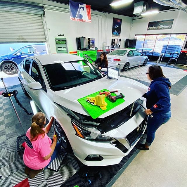 Students working real vehicles during paintless dent repair training at the Dent Time shop in Escondido