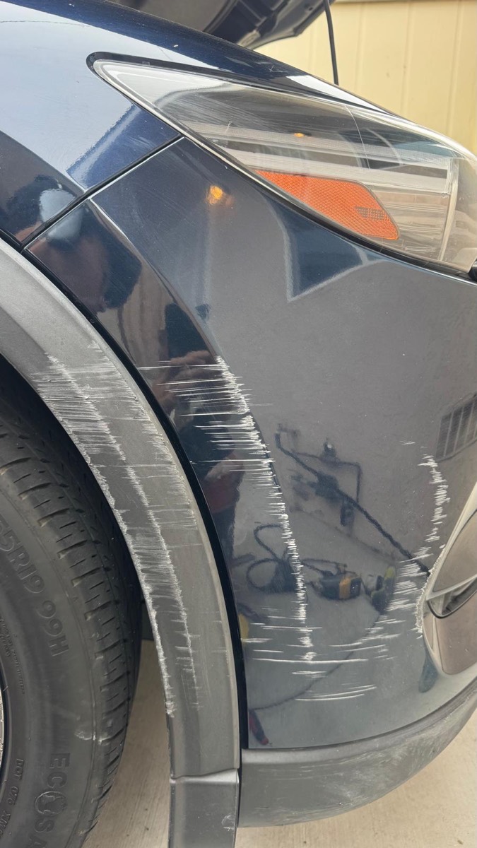 Deep scrape across the front fender and wheel arch trim of a dark blue SUV before repair in Escondido